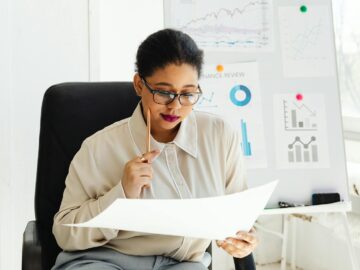Businesswoman in glasses analyzing financial documents at her office desk.