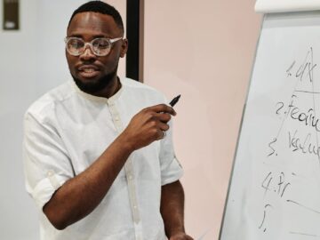 Man presenting at whiteboard in an office, explaining concepts with confidence.
