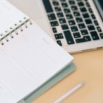 Open notebook next to a laptop and pen on a desk, ideal for business and planning.