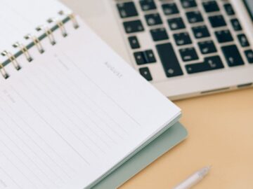 Open notebook next to a laptop and pen on a desk, ideal for business and planning.