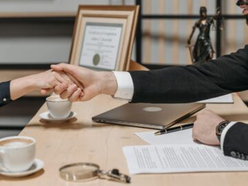 A formal handshake over a business contract in a corporate office setting.
