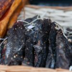 A close-up view of dried, seasoned meat slices displayed in a wicker basket.