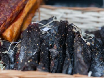 A close-up view of dried, seasoned meat slices displayed in a wicker basket.