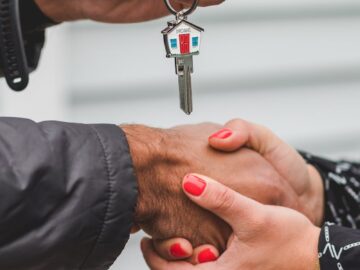 Close-up of a handshake with a house key, symbolizing real estate transactions.