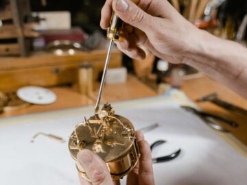 Close-up of a watchmaker using a screwdriver to repair a timepiece in a workshop.