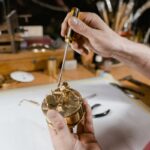 Close-up of a watchmaker using a screwdriver to repair a timepiece in a workshop.