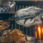 Closeup of fresh tilapia fish being grilled on a charcoal grill, perfect for seafood lovers.