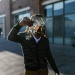 A person on city streets burning US dollar bills symbolizing cryptocurrency like Bitcoin.