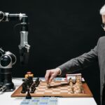 A bearded man strategically moves chess pieces while an AI robot arm assists in a futuristic game.