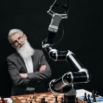A robotic arm versus a thoughtful man in a strategic chess game indoors.