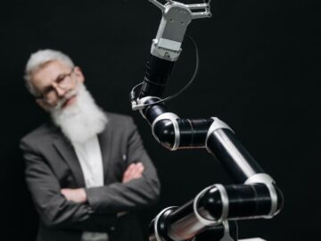 A robotic arm versus a thoughtful man in a strategic chess game indoors.