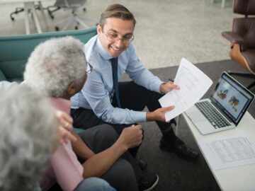 Financial advisor discussing documents with senior clients in an office setting, showcasing a collaborative consulting session.