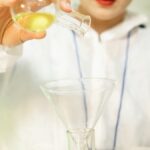 A scientist in protective gear pours a liquid into a flask, showcasing laboratory research.