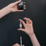 Close-up of hands holding glucometer, syringe, and ampoule against a dark background, representing healthcare themes.