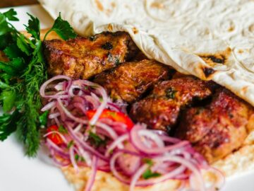Close-up of a grilled kebab with onions and herbs, perfect for a tasty meal.