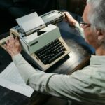An adult man using a vintage typewriter in an office setting, capturing a timeless moment.