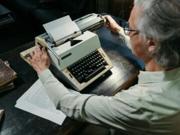 An adult man using a vintage typewriter in an office setting, capturing a timeless moment.