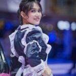 A smiling woman in a maid costume poses confidently, highlighting cosplay culture.