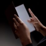 Unrecognizable person holding a diploma against a black background, symbolizing achievement and education.