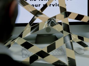 A man views a rejection message on a computer screen blocked by caution tape, symbolizing unemployment.