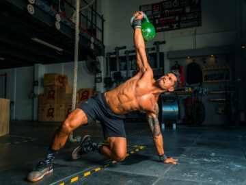 man in black shorts and black tank top doing push up