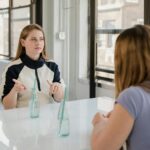 Two women sitting at a table indoors, communicating using sign language, showcasing friendship and inclusivity.