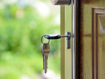 Key inserted in door lock against a blurred green background, symbolizing security and real estate.