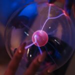 Close-up of adult hands interacting with a glowing plasma ball.