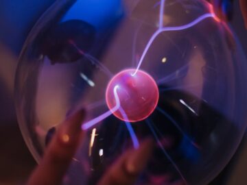 Close-up of adult hands interacting with a glowing plasma ball.