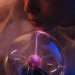 Close-up of woman interacting with a glowing plasma globe, showcasing electricity patterns.