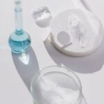 Glassware on a white surface casting shadows, ideal for scientific themes.