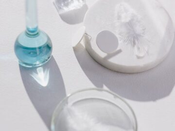 Glassware on a white surface casting shadows, ideal for scientific themes.