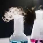 Steam rising from colorful liquid in glass flasks during a lab experiment.