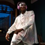 An adult man dancing energetically indoors while listening to music on headphones.