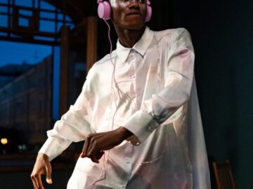 An adult man dancing energetically indoors while listening to music on headphones.