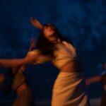 Blurred movement of women dancing joyfully during nighttime, creating an ecstatic and dreamy atmosphere.