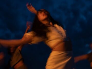Blurred movement of women dancing joyfully during nighttime, creating an ecstatic and dreamy atmosphere.