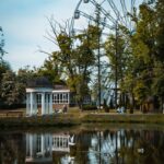 A beautiful park landscape with a Ferris wheel and serene lake reflections.