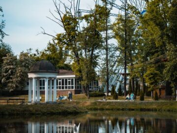 A beautiful park landscape with a Ferris wheel and serene lake reflections.