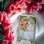The Lovers tarot card among vibrant pink tulips symbolizing love and harmony.