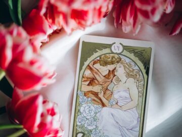 The Lovers tarot card among vibrant pink tulips symbolizing love and harmony.