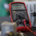 Close-up shot of a multimeter used for electrical measurements, with focus on the display.