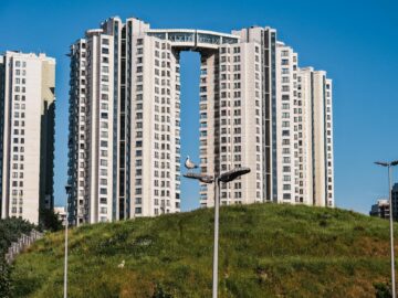 Capture of a modern high-rise building in İstanbul with a seagull perched, clear sky backdrop.