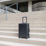 A sleek modern suitcase positioned on concrete steps outside a building in Greensboro, NC.