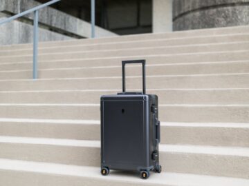 A sleek modern suitcase positioned on concrete steps outside a building in Greensboro, NC.