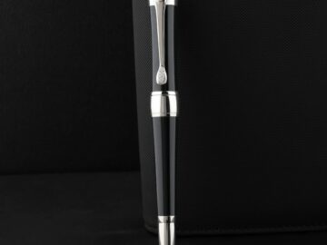 Sleek black pen with silver accents on a textured black surface, exuding elegance and luxury.