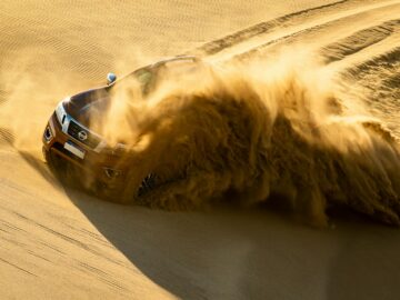 Dynamic shot of an SUV kicking up sand as it speeds through dunes in Cariló, Argentina.