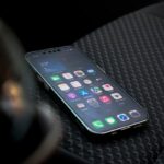 Close-up view of a smartphone displaying apps on a car seat highlighting connectivity.