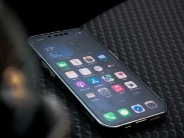 Close-up view of a smartphone displaying apps on a car seat highlighting connectivity.