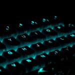 Close-up of a glowing gaming keyboard with blue backlighting in a dark ambiance.